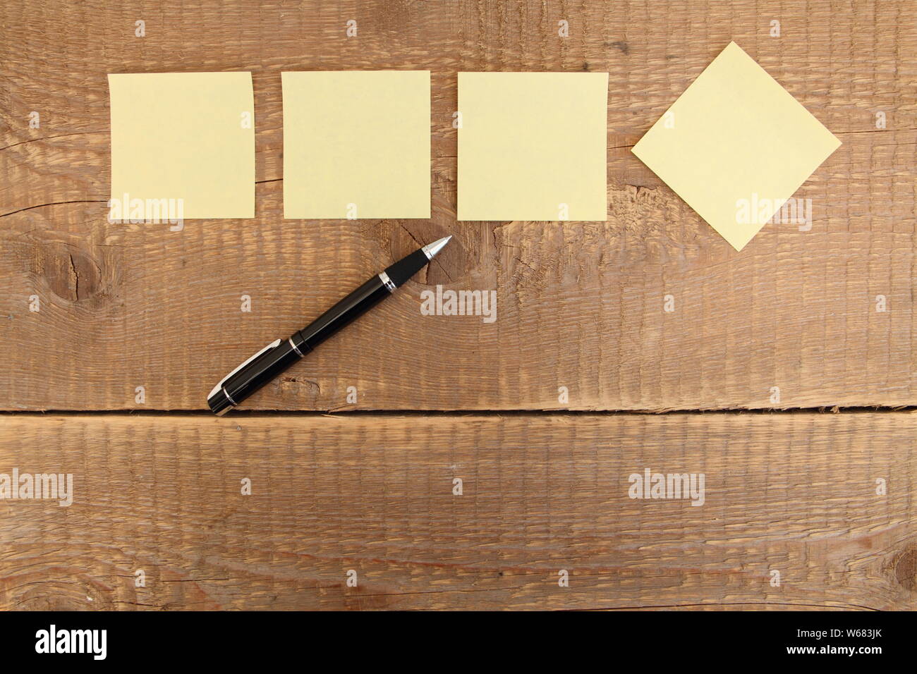 four yellow notes on a wooden table Stock Photo