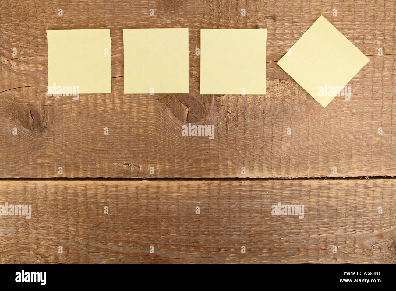 four yellow notes on a wooden table Stock Photo