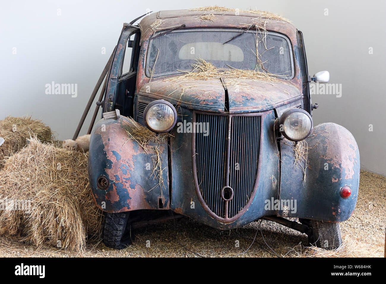 Abandoned old wrecked rusty car standing in an corner of some old barn Stock Photo