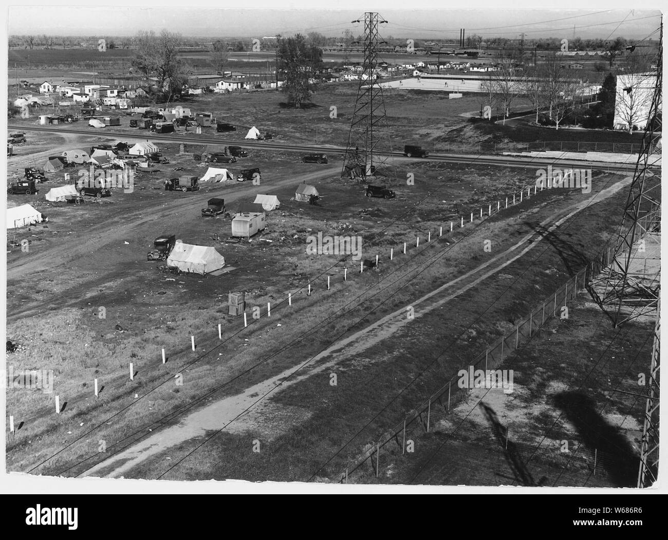 Sacramento, California. Squatter camp of agricultural labor migrants one-eighth mile outside limits . . .; Scope and content:  Full caption reads as follows: Sacramento, California. Squatter camp of agricultural labor migrants one-eighth mile outside limits of state capital of California. Above 125 units, without sanitation; water donated by power company from single faucet. Across the main road (upper right of panel) is a trailer camp. Beyond is newly developing shacktown community where lots are being sold and families are settling in makeshift homebuilt cabins and cottages of all descriptio Stock Photo