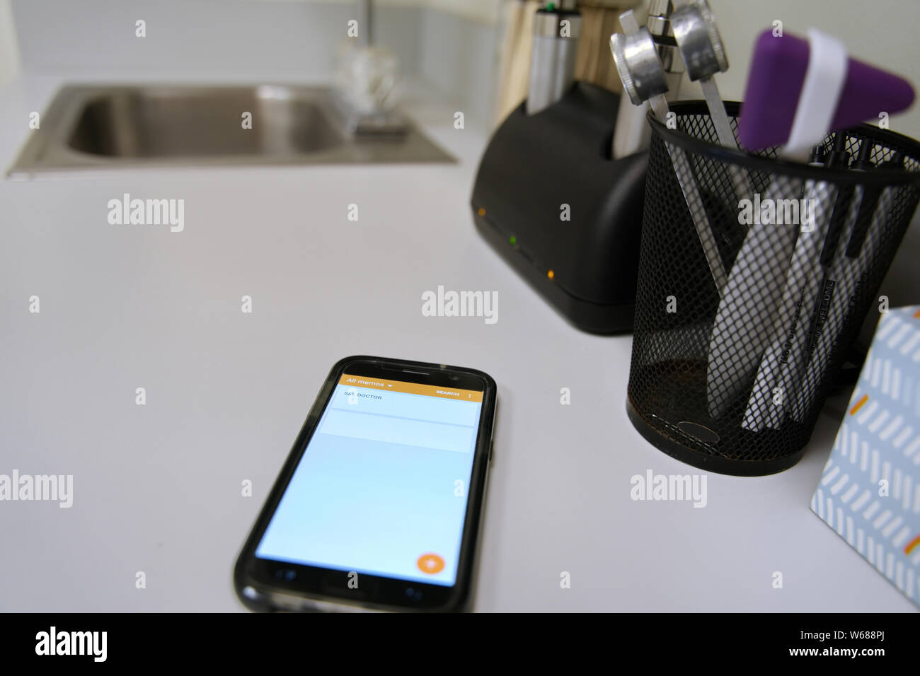 Smartphone on clinic table displaying an important note to seek medical attention. Stock Photo