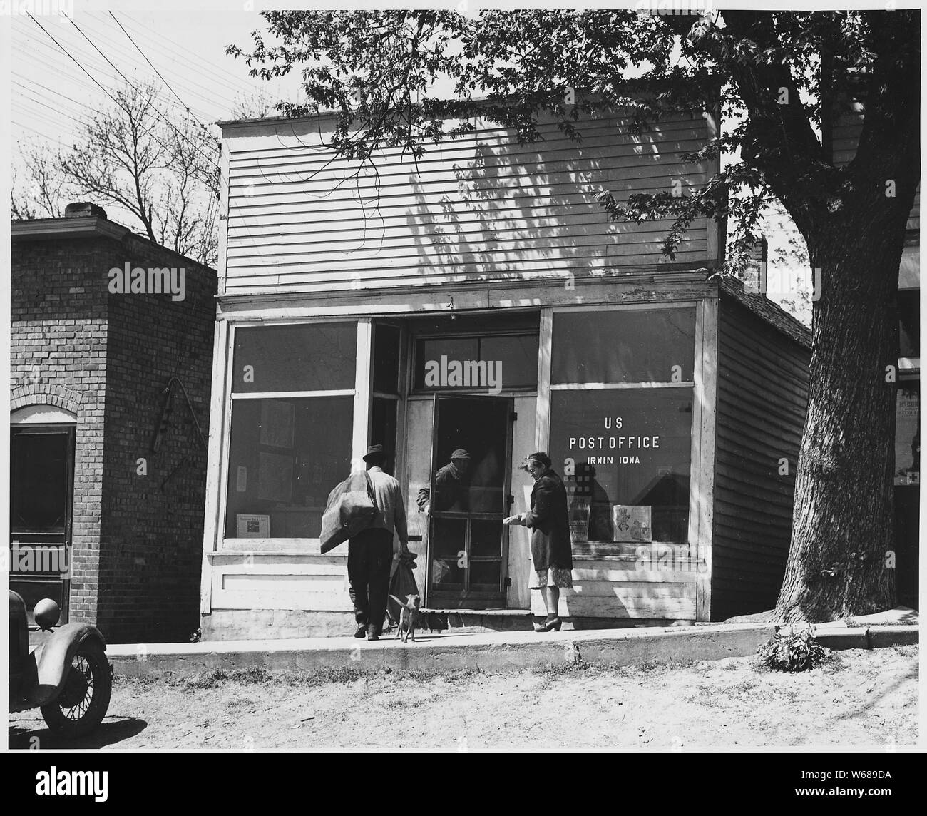 Shelby County, Iowa. Several trains a day top at the Irwin depot, most of them just long enough to d . . .; Scope and content:  Full caption reads as follows: Shelby County, Iowa. Several trains a day top at the Irwin depot, most of them just long enough to drop the mail. The post mistress generally carries the mail sack herself from the station to the Post Office fifty yards away. Stock Photo