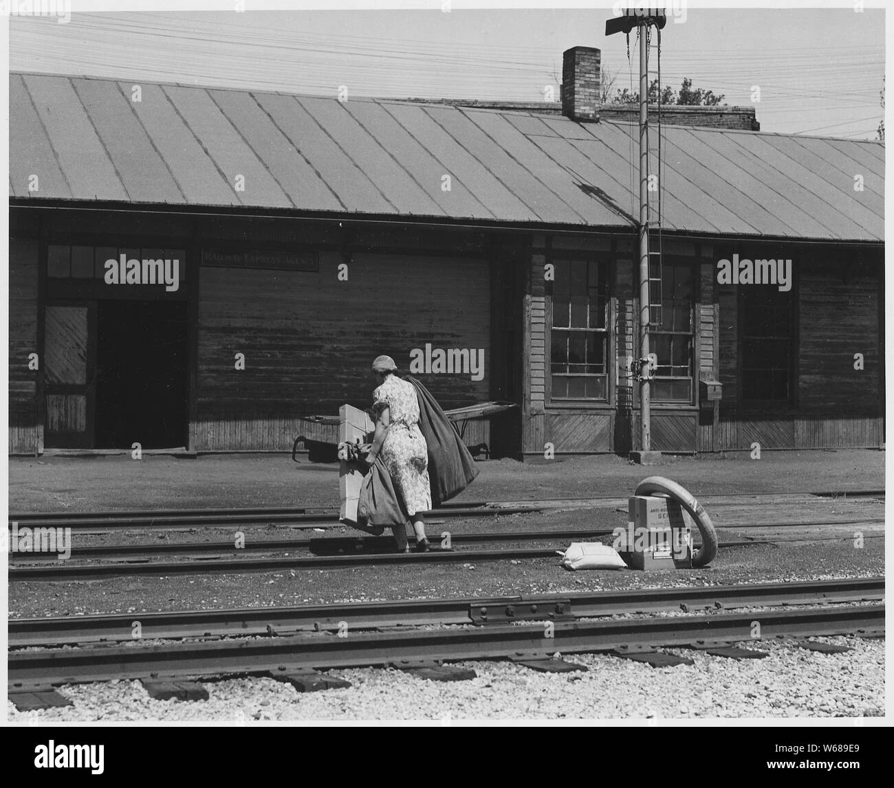 Shelby County, Iowa. Several trains a day stop at the Irwin depot, most of them just long enough to . . .; Scope and content:  Full caption reads as follows: Shelby County, Iowa. Several trains a day stop at the Irwin depot, most of them just long enough to drop the mail. The post mistress generally carries the mail sack herself from the station to the Post Office fifty yards away. Stock Photo