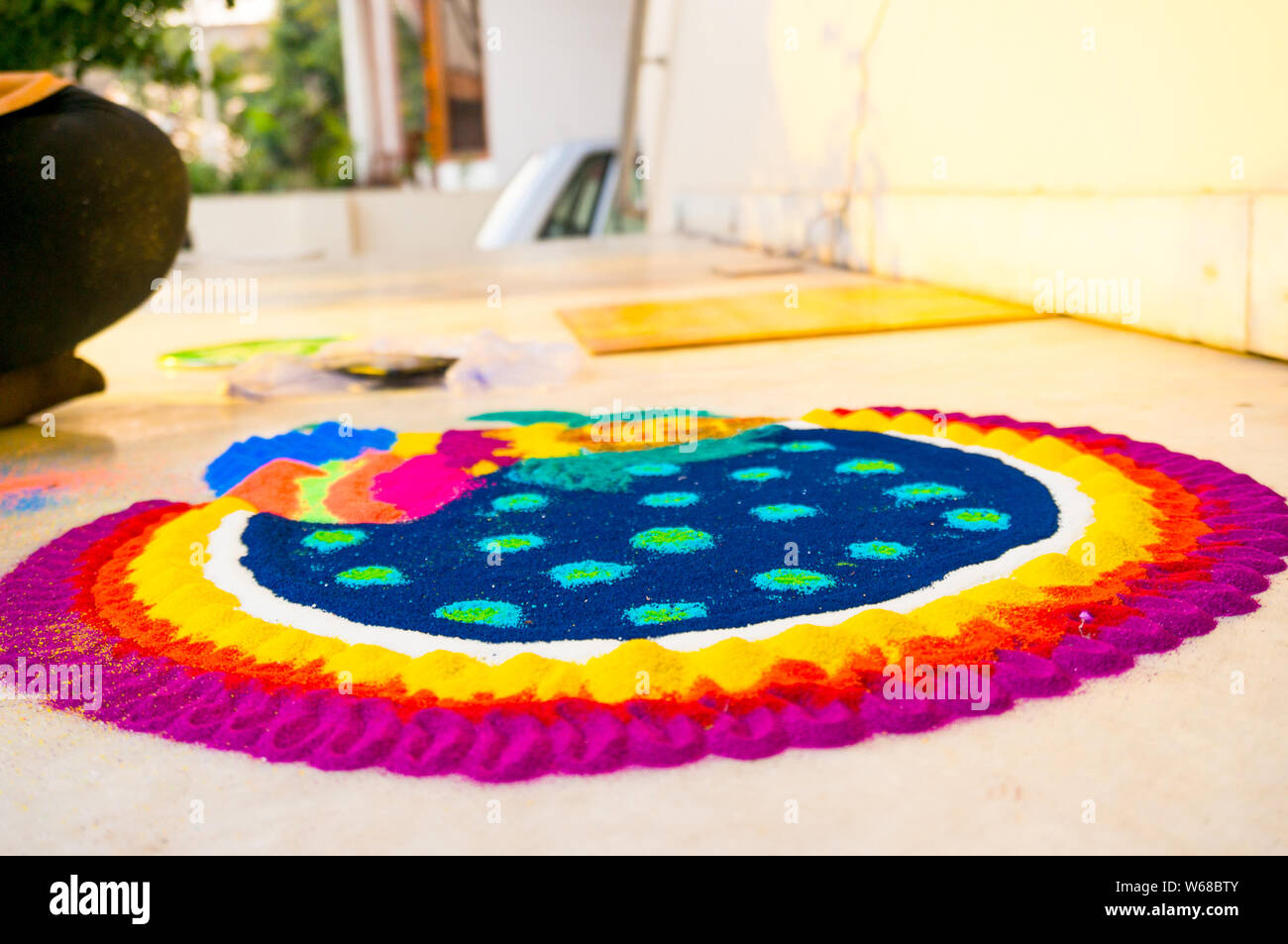 Rangoli being made on a marble stone floor with colored powder on eve