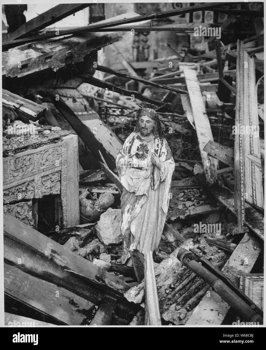 Still standing in the rubble of a church in the war-blasted town of Dulag, a statue of the sacred heart appears to gaze in quiet sorrow on the destruction wrought by battle's fury seething over Leyte Island. Philippines, 1944.; General notes:  Use War and Conflict Number 1331 when ordering a reproduction or requesting information about this image. Stock Photo