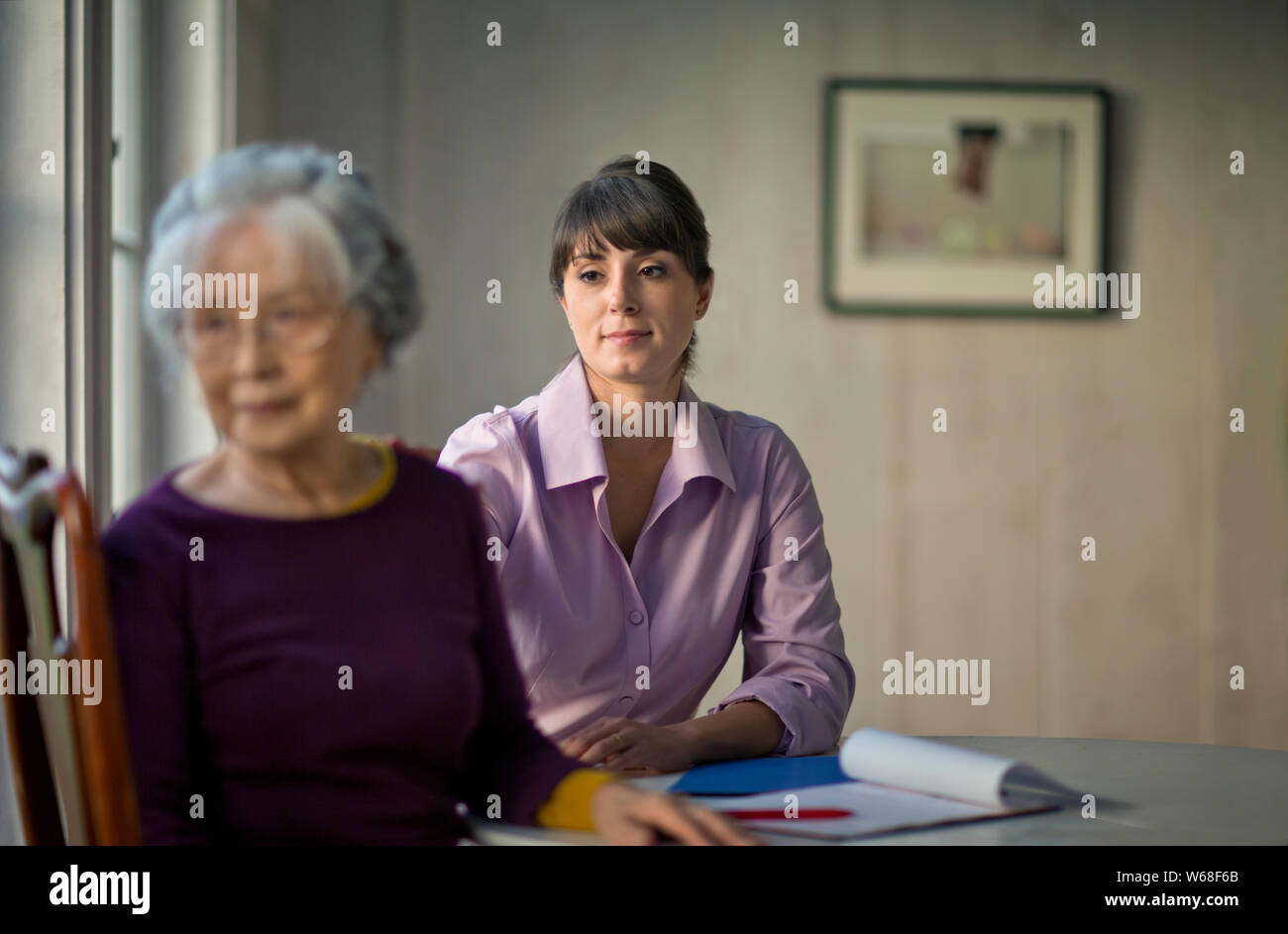 Young female doctor sitting with an elderly patient. Stock Photo