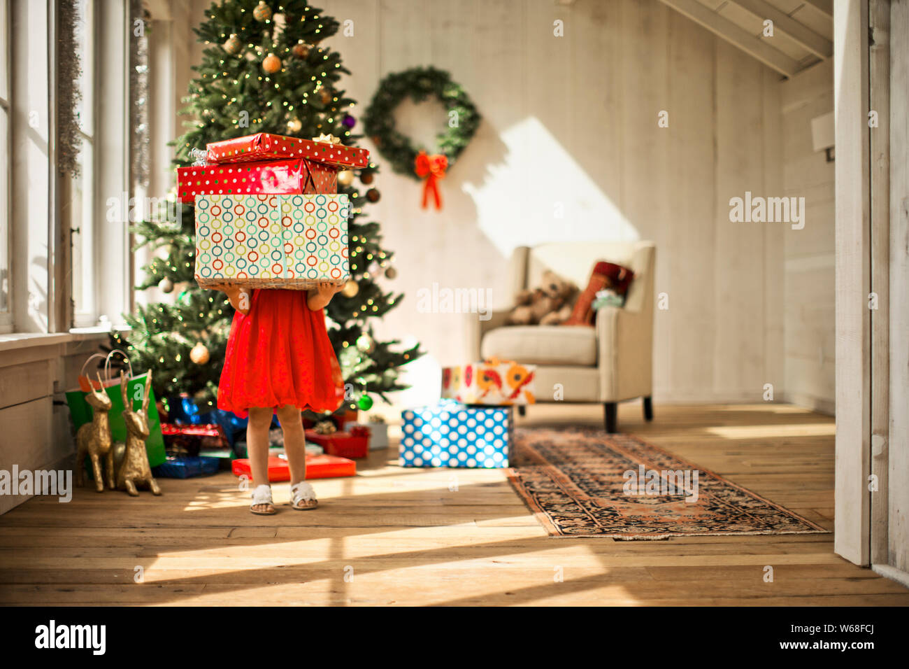 Young girl carrying a stack of Christmas presents. Stock Photo