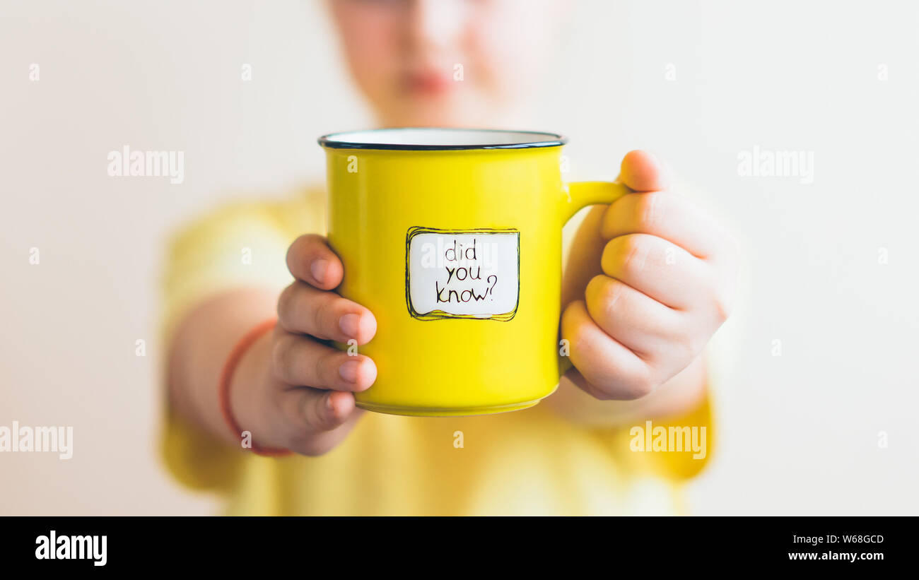 A girl with a yellow cup in her hand, on which was written Did you know Stock Photo