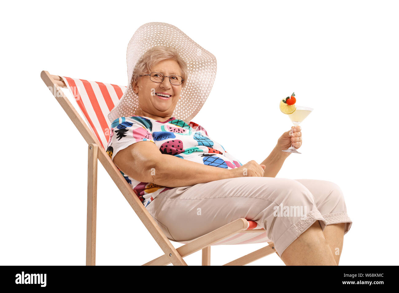 Mature woman with a cocktail sitting on a deck chair isolated on white background Stock Photo