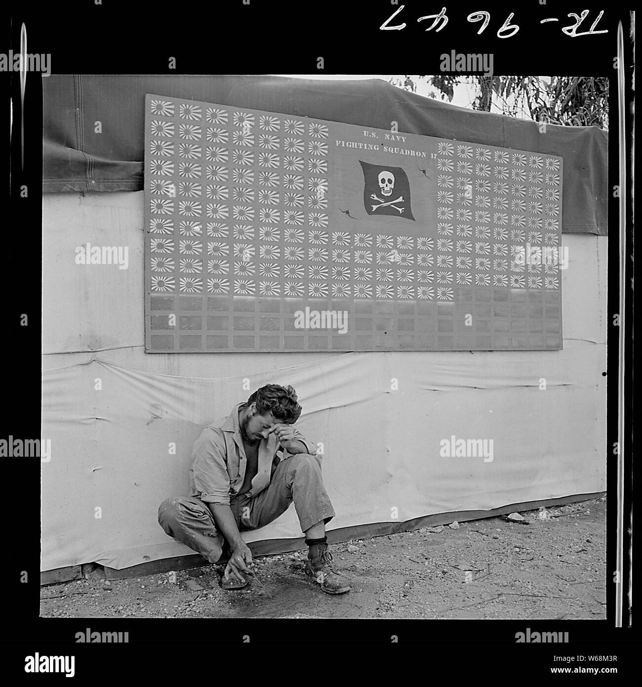 Tired member of VF-17 pauses under squadron scoreboard at Bougainville.; General notes:  Use War and Conflict Number 1195 when ordering a reproduction or requesting information about this image. Stock Photo