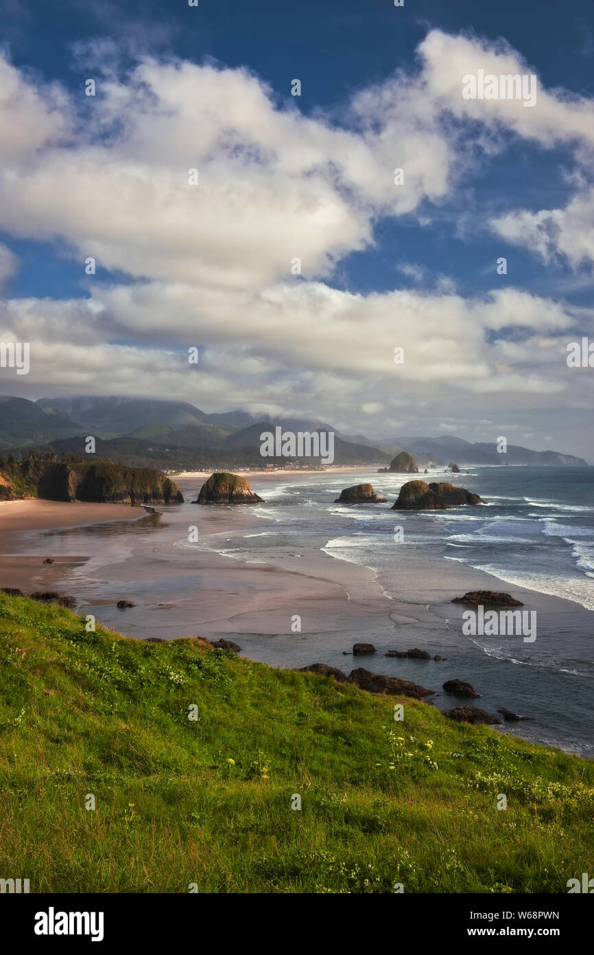Clouds and fog lift over Neahkahnie Mountain revealing the spectacular view of Cannon Beach and offshore Haystack Rock from Oregon’s Ecola State Park. Stock Photo