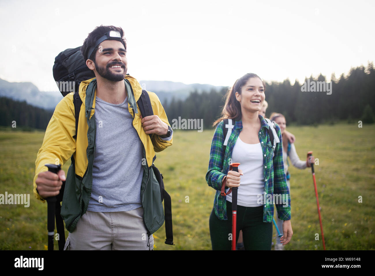 Backpackers happy young couple hiking with sticks Stock Photo - Alamy