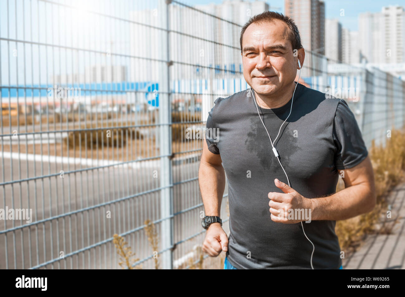 Mature man doing jogging on a city street. Senior man leads a healthy and active lifestyle playing sports. Stock Photo