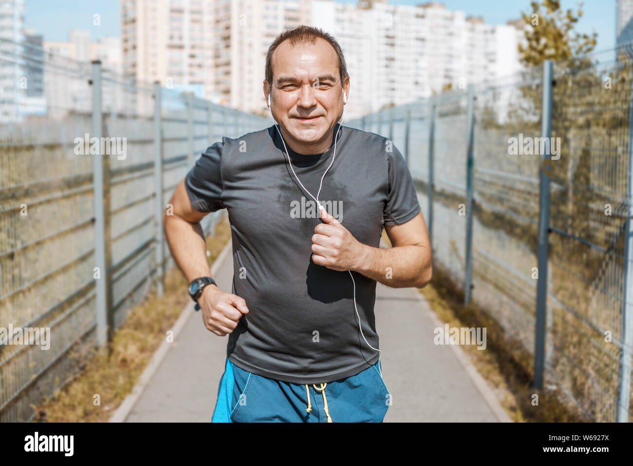 Mature man doing jogging on a city street. Senior man leads a healthy and active lifestyle playing sports. Stock Photo