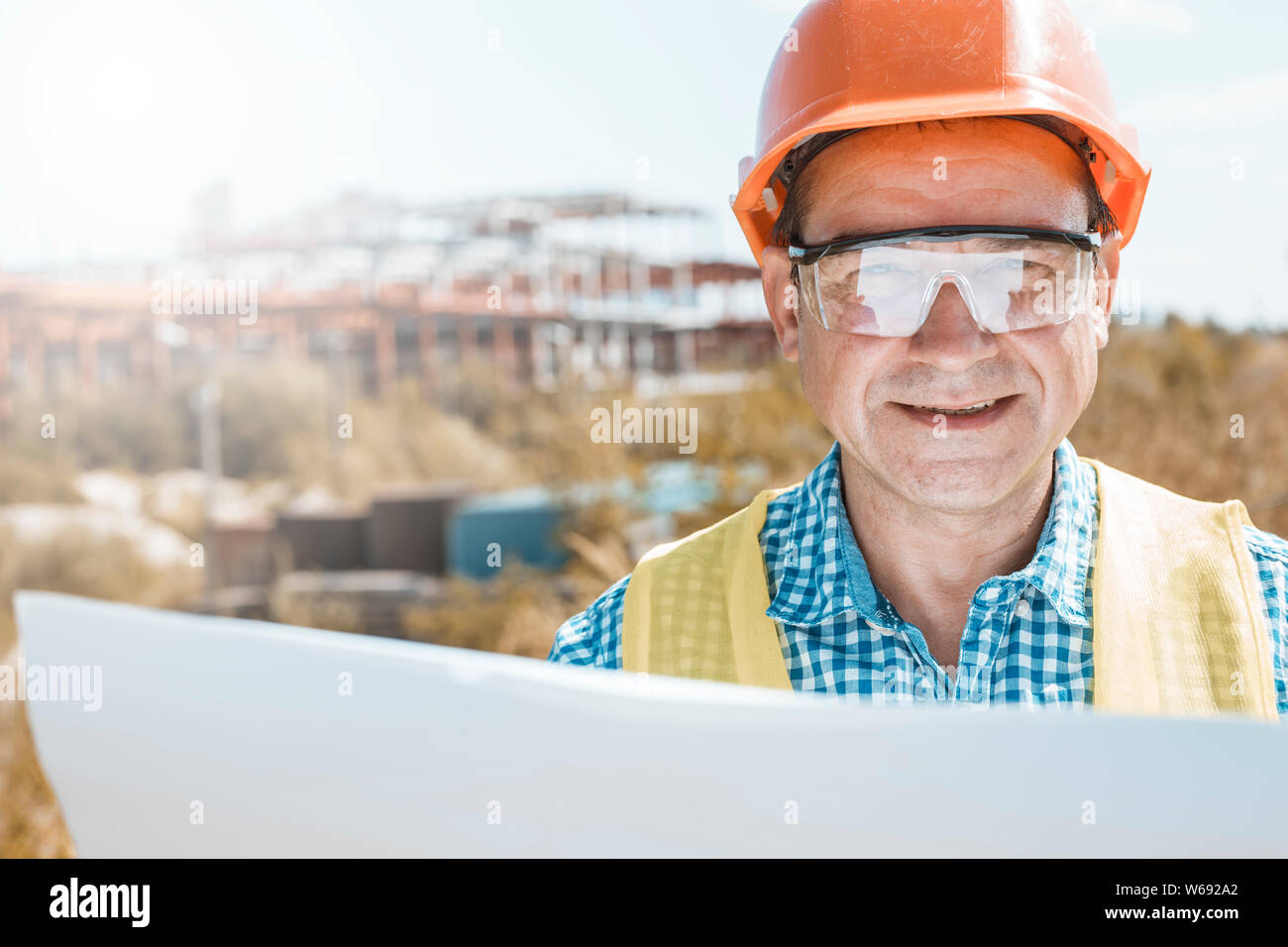 Male builder, architect or engineer in a helmet and glasses on a construction site. Stock Photo
