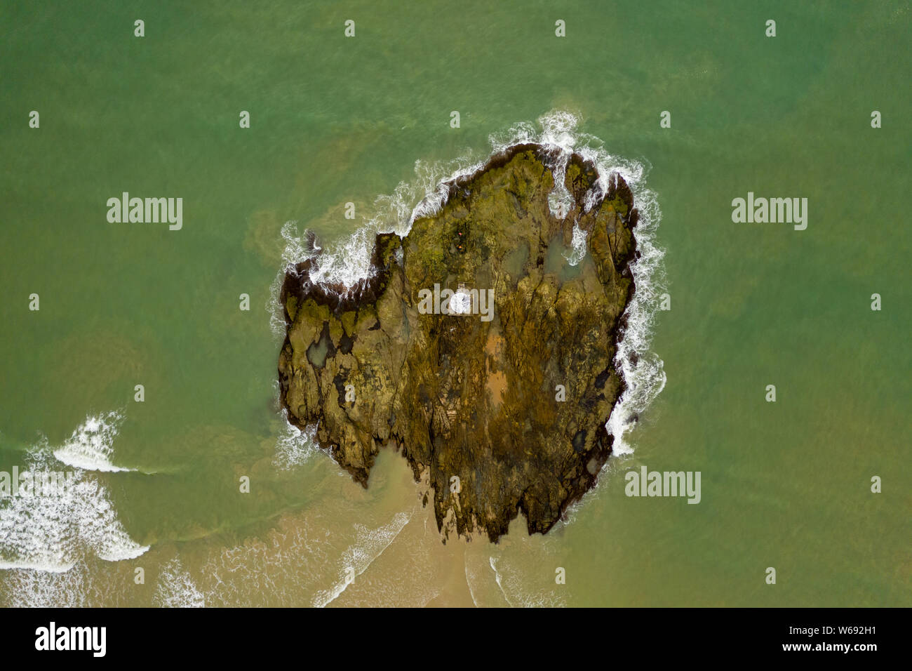 Top down aerial view of a lighthouse on a small rocky island surrounded ...