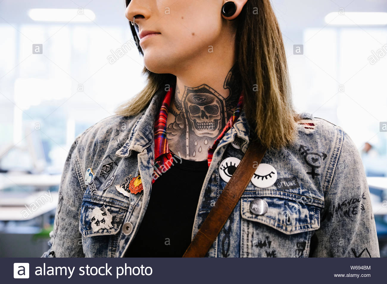 Student with tattoos on neck wearing denim jacket Stock Photo