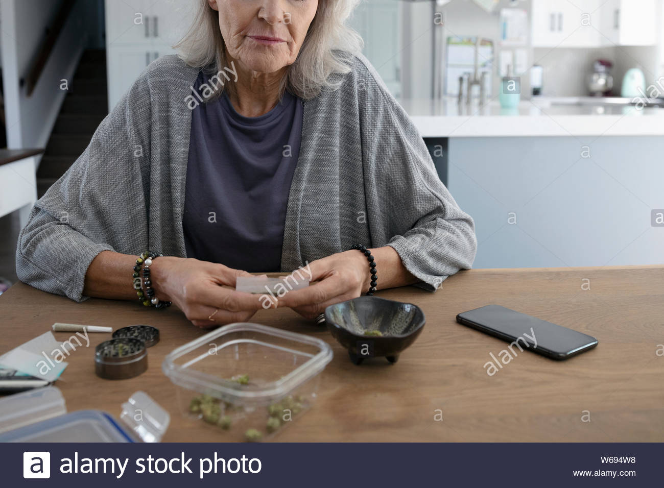 Senior woman rolling marijuana joints at dining table Stock Photo Alamy