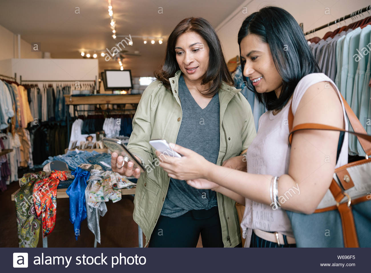Women with smart phones shopping in clothing store Stock Photo
