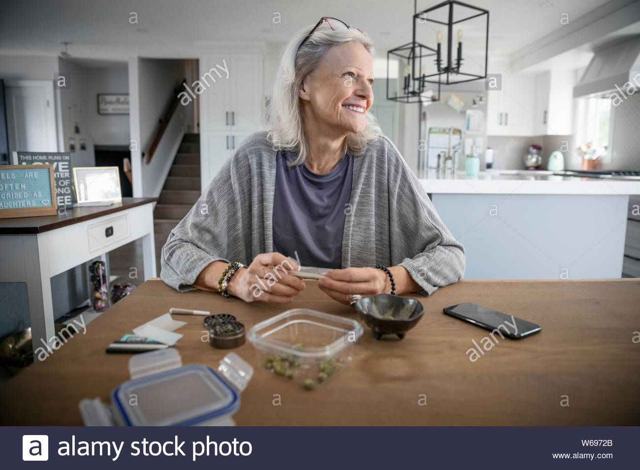 Senior woman rolling marijuana joints at dining table Stock Photo Alamy