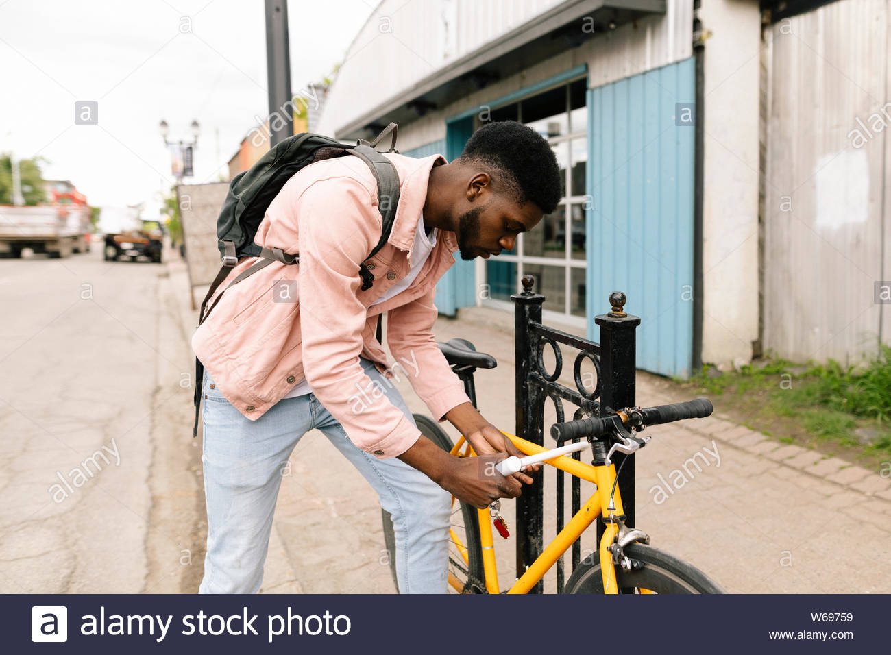 Young man locking bicycle on sidewalk Stock Photo