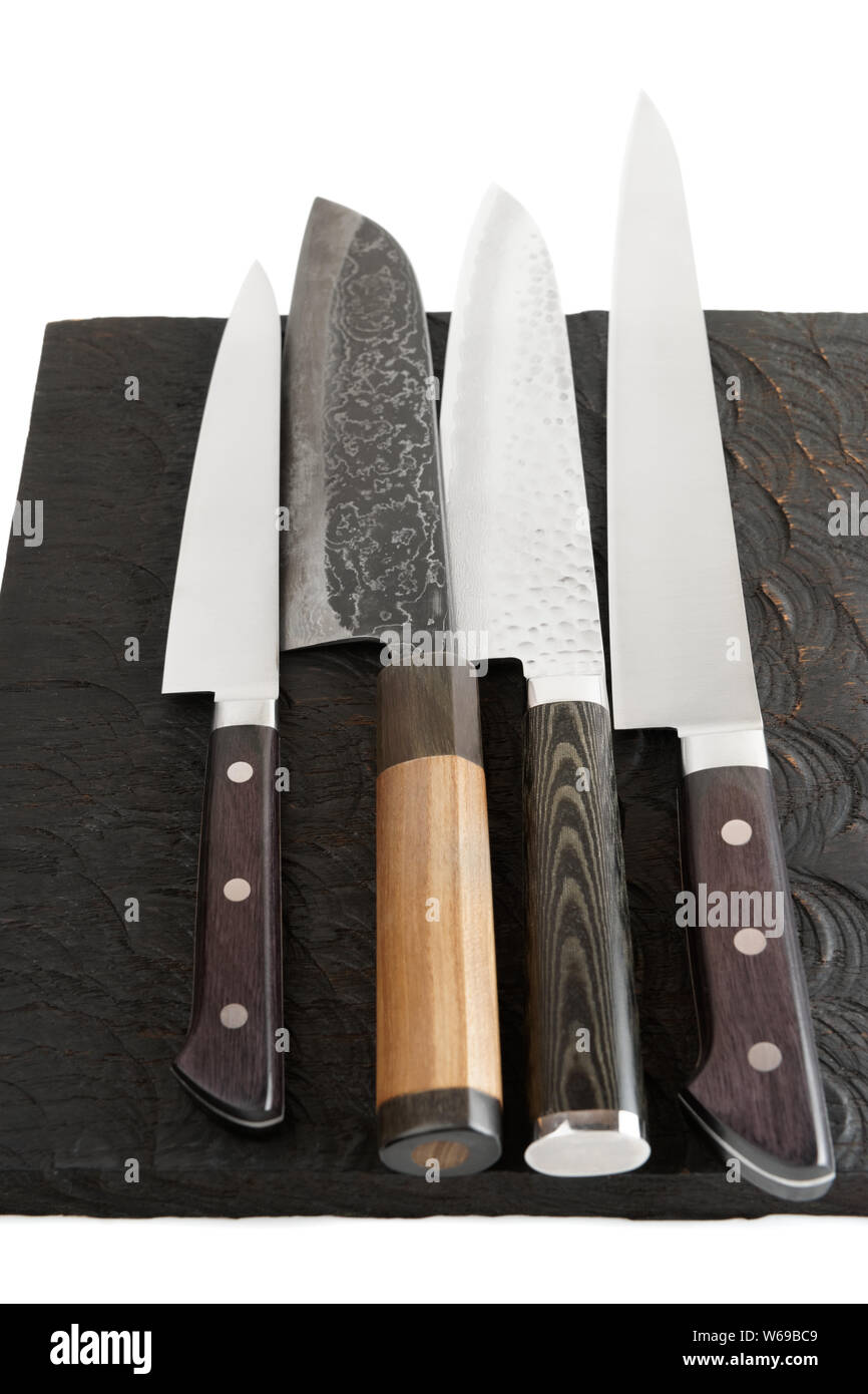 Four different knives on black wooden cutting board Stock Photo