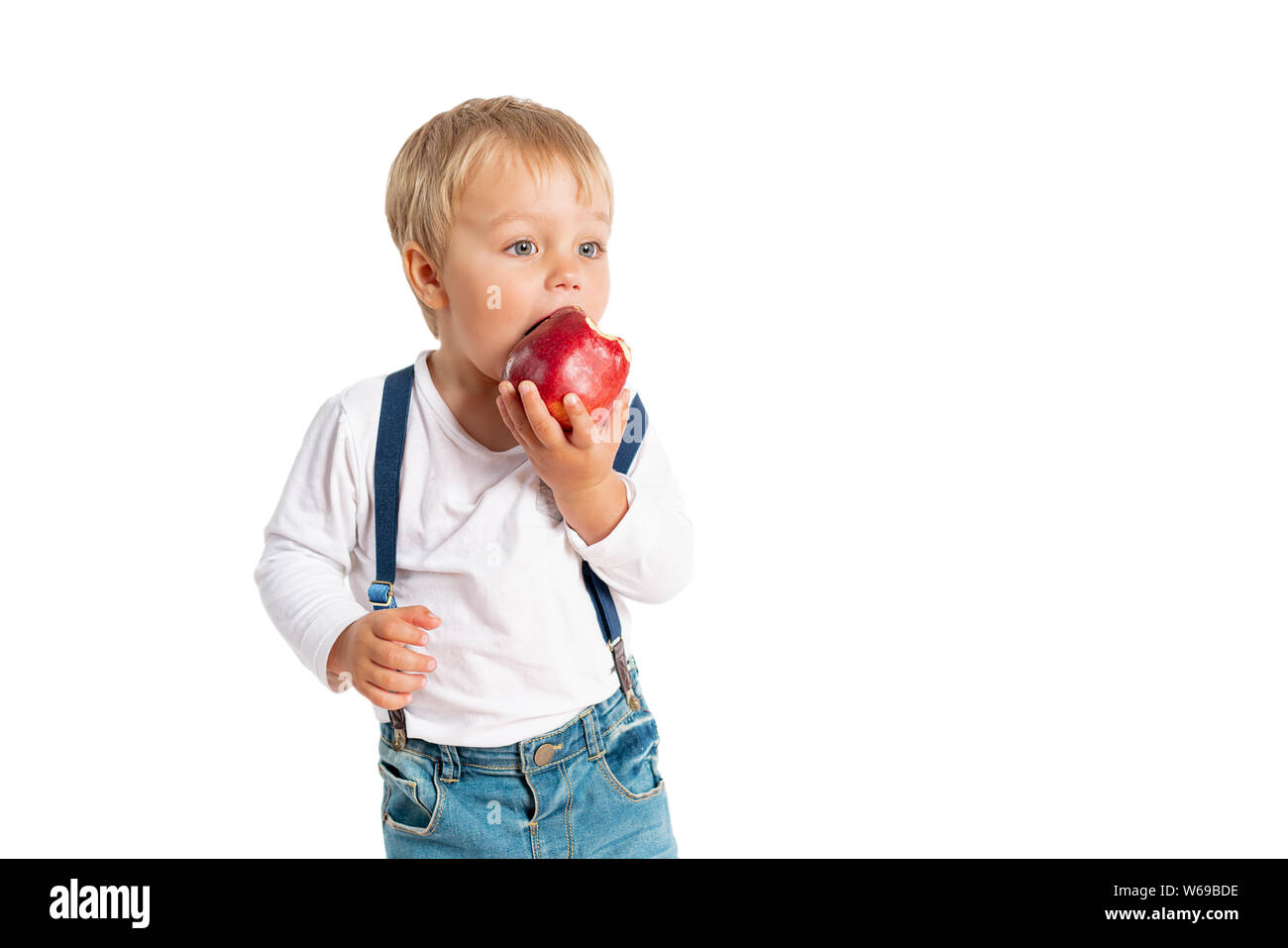 Baby boy eating apple and smiling in the studio isolated on white background Stock Photo