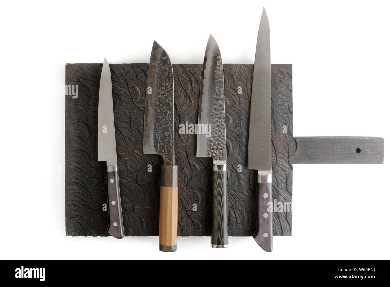 Four different knives on black cutting board, isolated on white with shadows Stock Photo