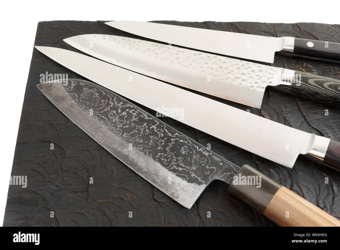 Four different knives on black wooden cutting board Stock Photo