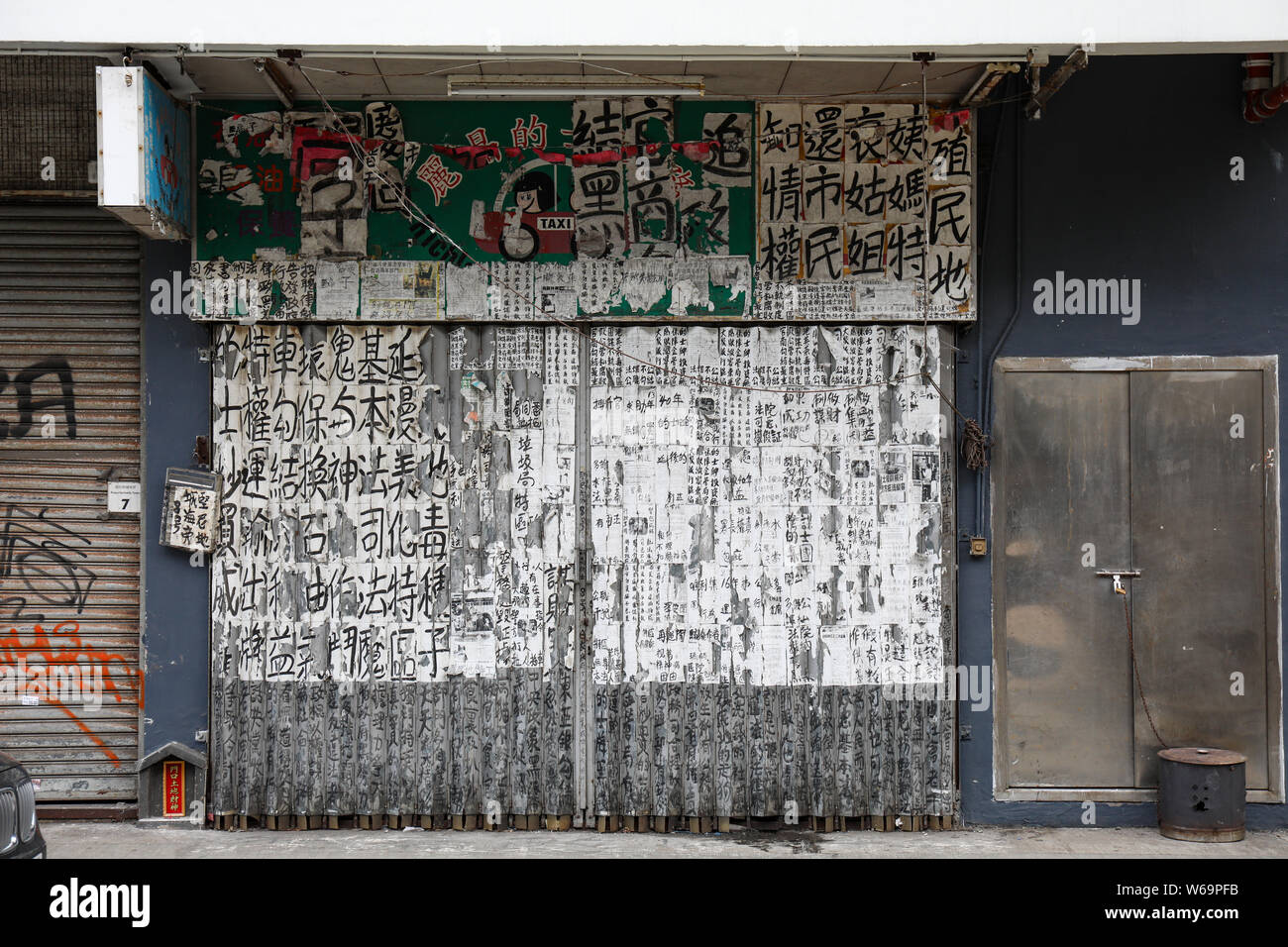 Folding shop, garage, warehouse or workshop door coated with paper and Chinese characters in Hong Kong Stock Photo