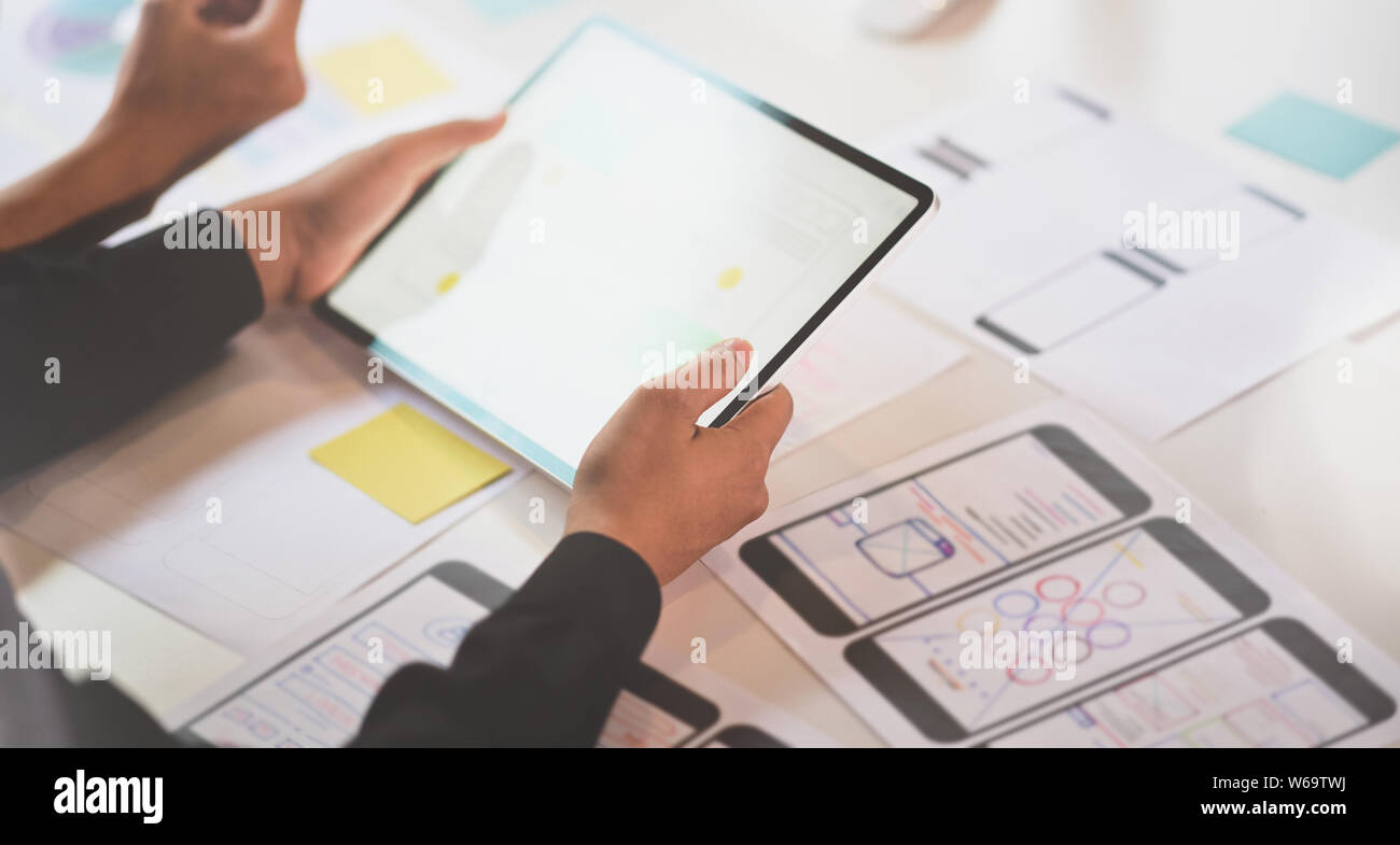 UI designer discussing on interface project while using tablet Stock Photo