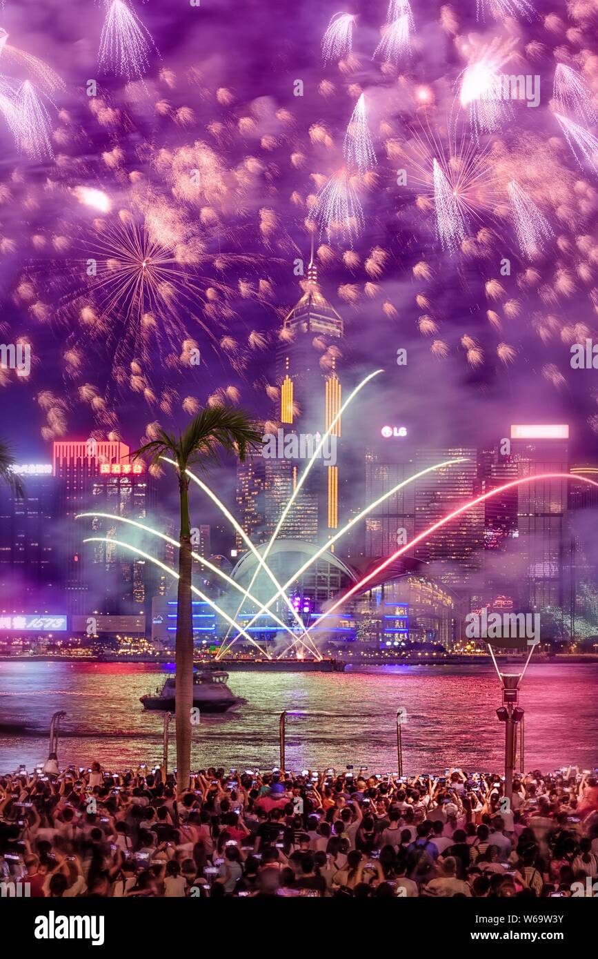 Vertical shot of breathtaking beautiful fireworks in the sky over a large group of people and a lake Stock Photo