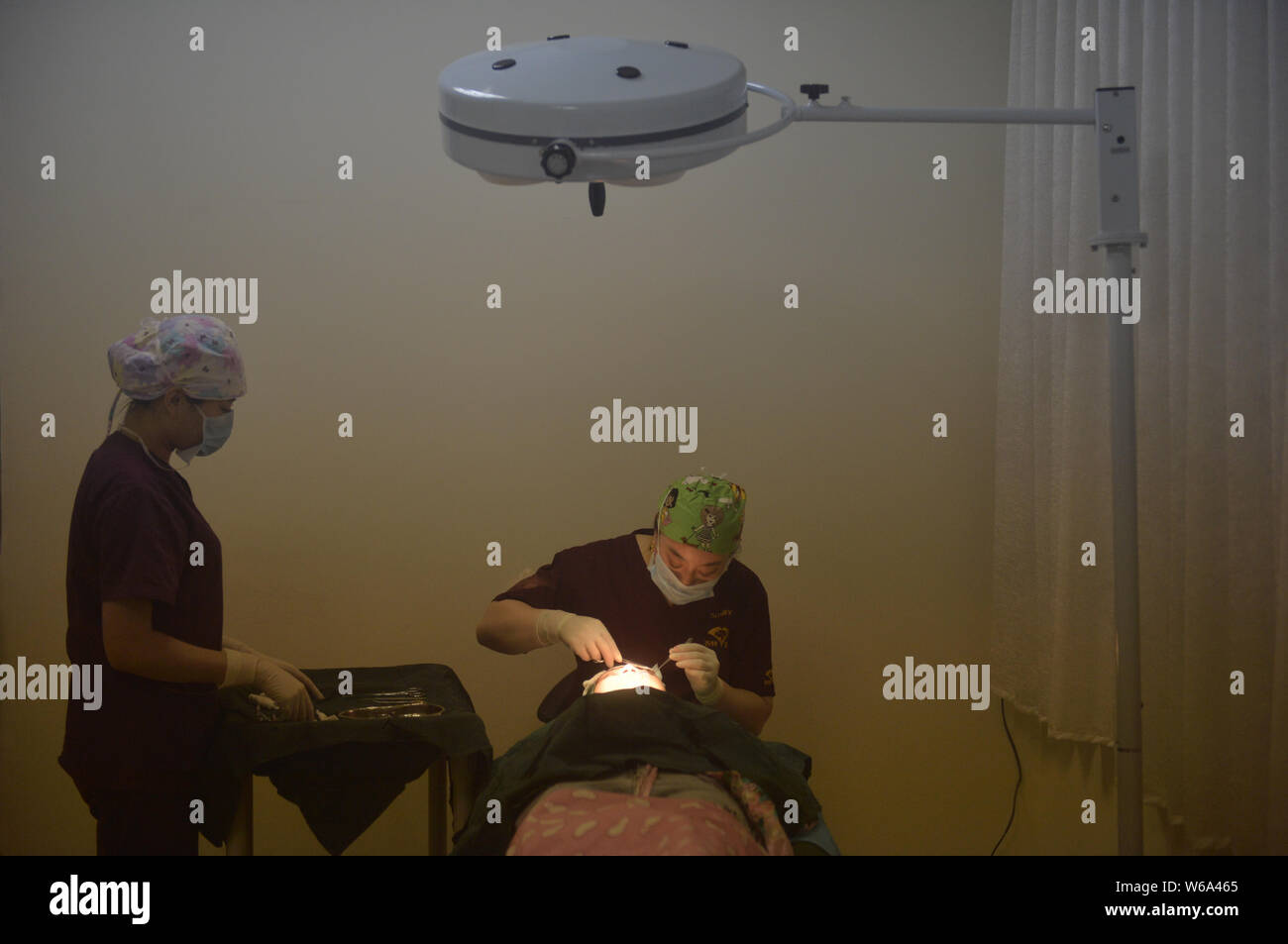 A doctor performs a cosmetic surgery on the eyes of a female young