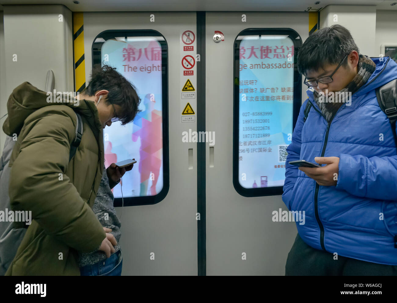 --FILE--Passengers use their smartphones to surf the Internet on a subway train in Chengdu city, southwest China's Sichuan province, 8 February 2018. Stock Photo