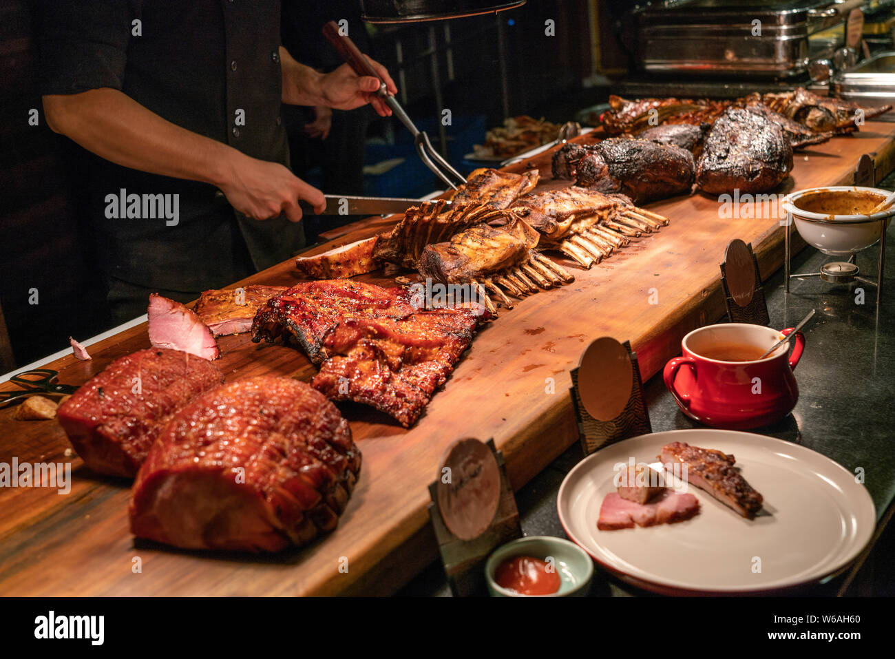 Chef in meat buffet counter cutting delicious grilled ribs Stock