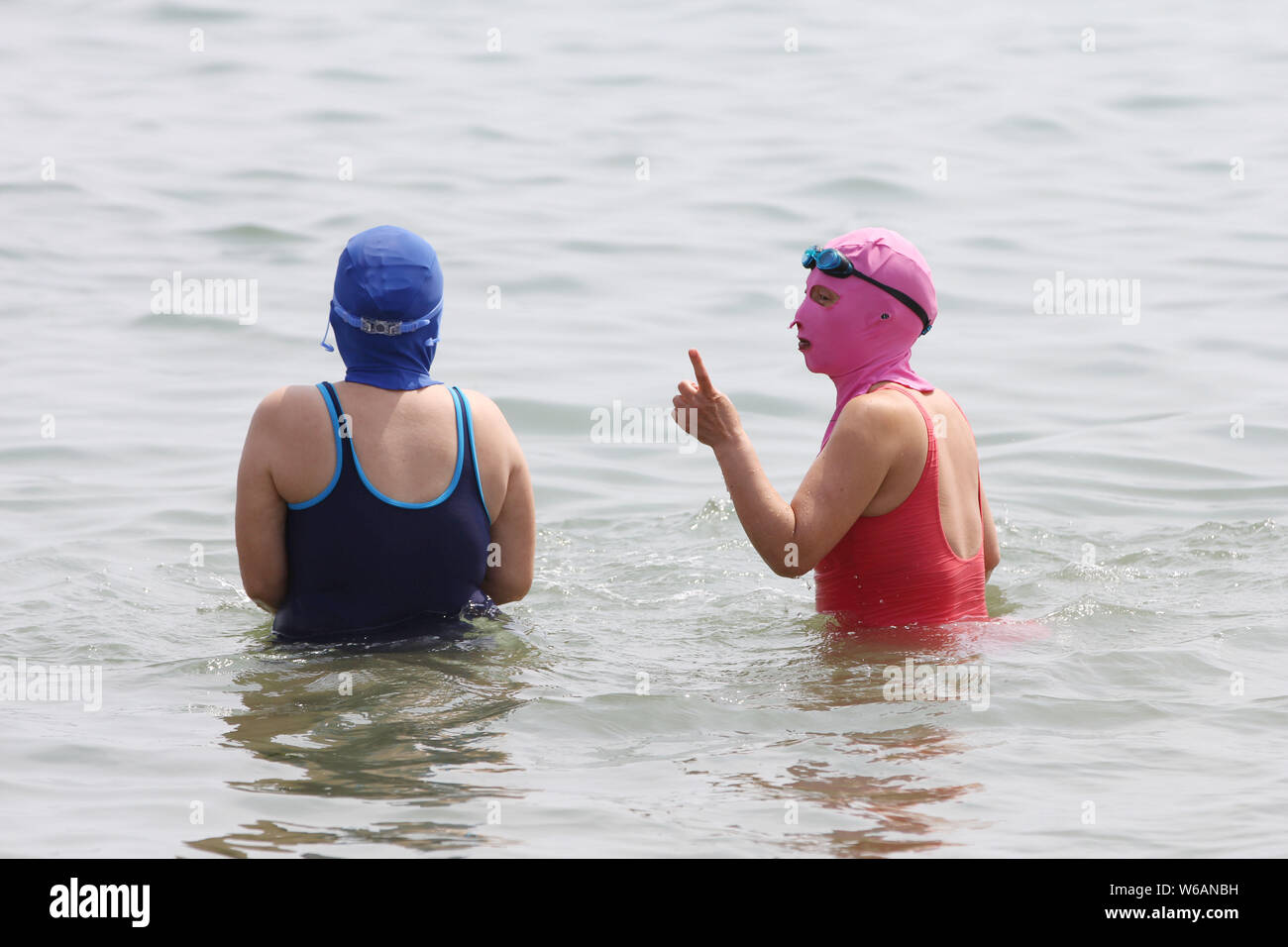 Chinese beachgoers wearing a facekini are pictured at a beach resort in
