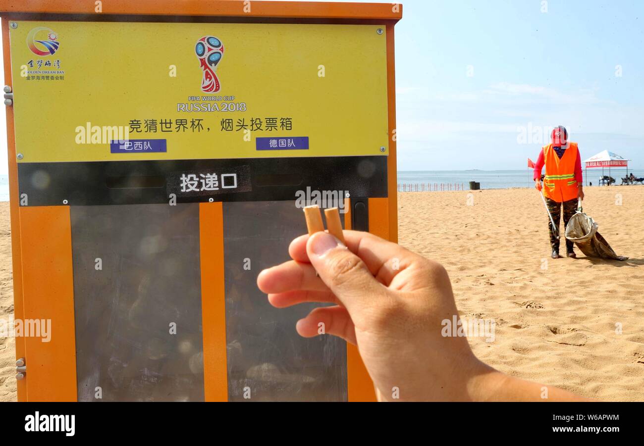 A local resident prepares to put cigarette ends into an ash can resembling a ballot box for World Cup prediction at a beach resort in Qinhuangdao city Stock Photo