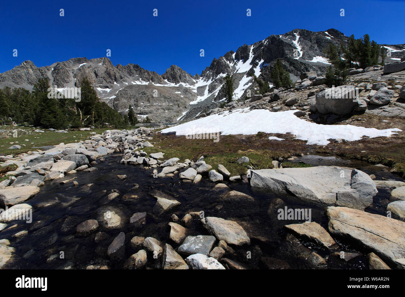Mammoth Lakes, CA—July 30, 2019. A rocky stream runs through snow from Pica Lake near Mammoth Lakes, CA. Stock Photo