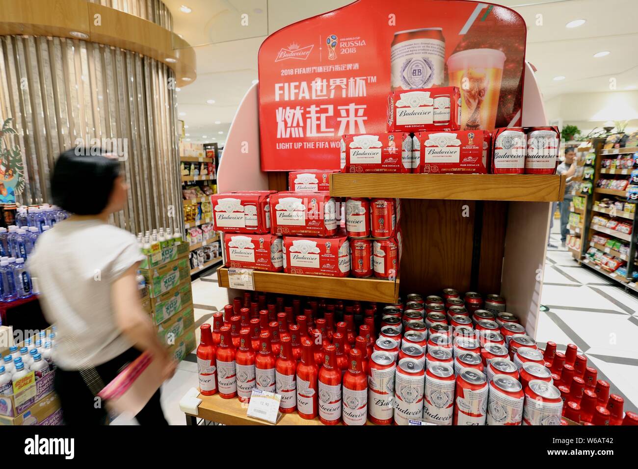 A customer walk past tins of Budweiser beer of Anheuser-Busch InBev Group for sale at a supermarket in Nanjing city, east China's Jiangsu province, 7 Stock Photo