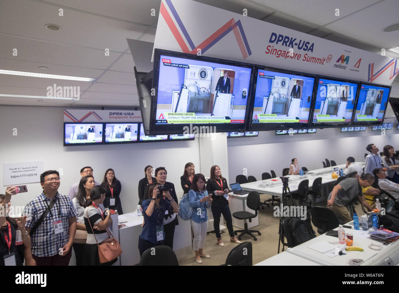 Journalists at the media center watch screens display that U.S. President  Donald Trump deplanes as his Air Force One arrives at the Paya Lebar Air Bas  Stock Photo - Alamy
