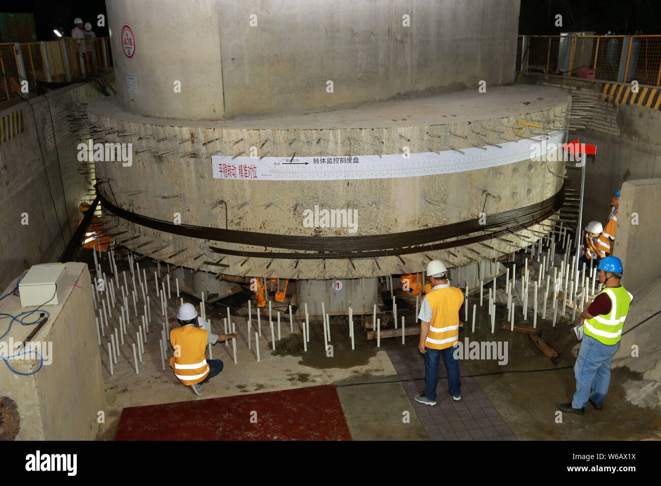 Chinese workers labor at a construction site to rotate a girder bridge ...