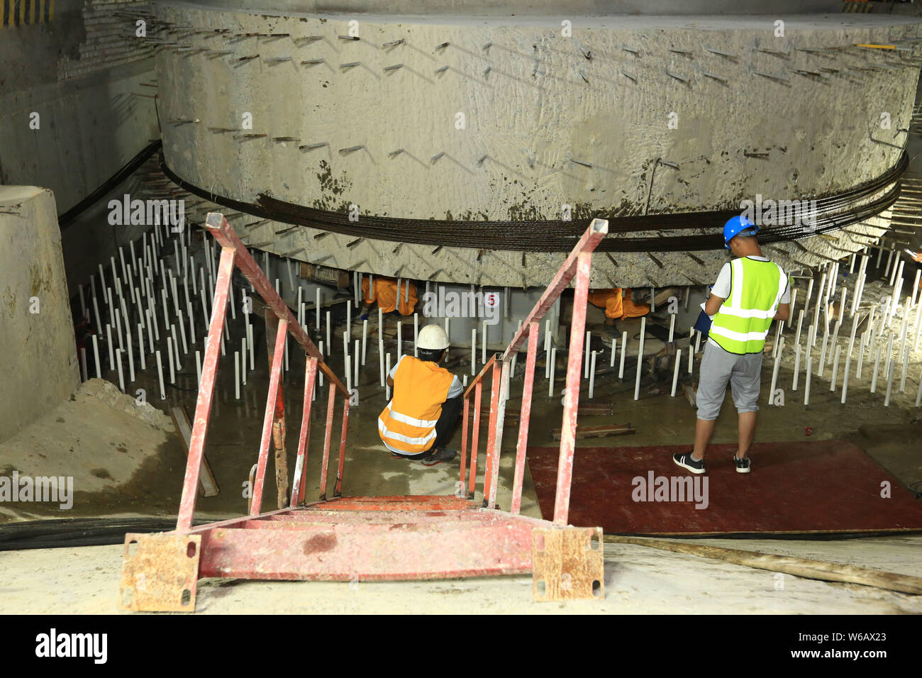 Chinese workers labor at a construction site to rotate a girder bridge ...