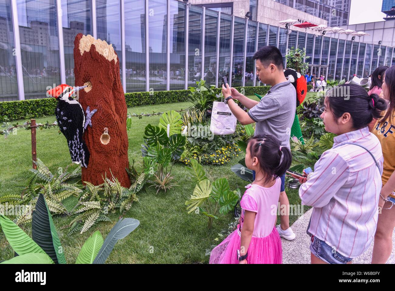 Visitors look at a Lego sculpture of woodpecker created by New York-based artist Sean Kenney during the 'Nature Connects' Lego exhibition at the Cheng Stock Photo