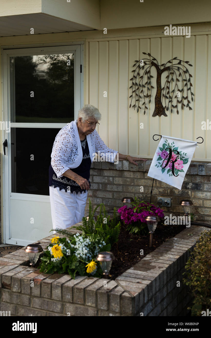 An elderly woman checks her flower garden outside her home in Warren, Indiana, USA. Stock Photo