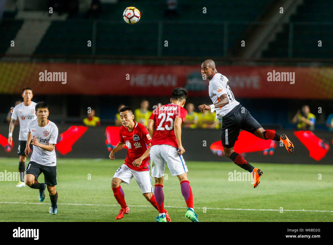 Ecuadorian football player Jaime Ayovi, top, of Beijing Renhe heads the ball to make a pass against players of Henan Jianye in their 10th round match Stock Photo