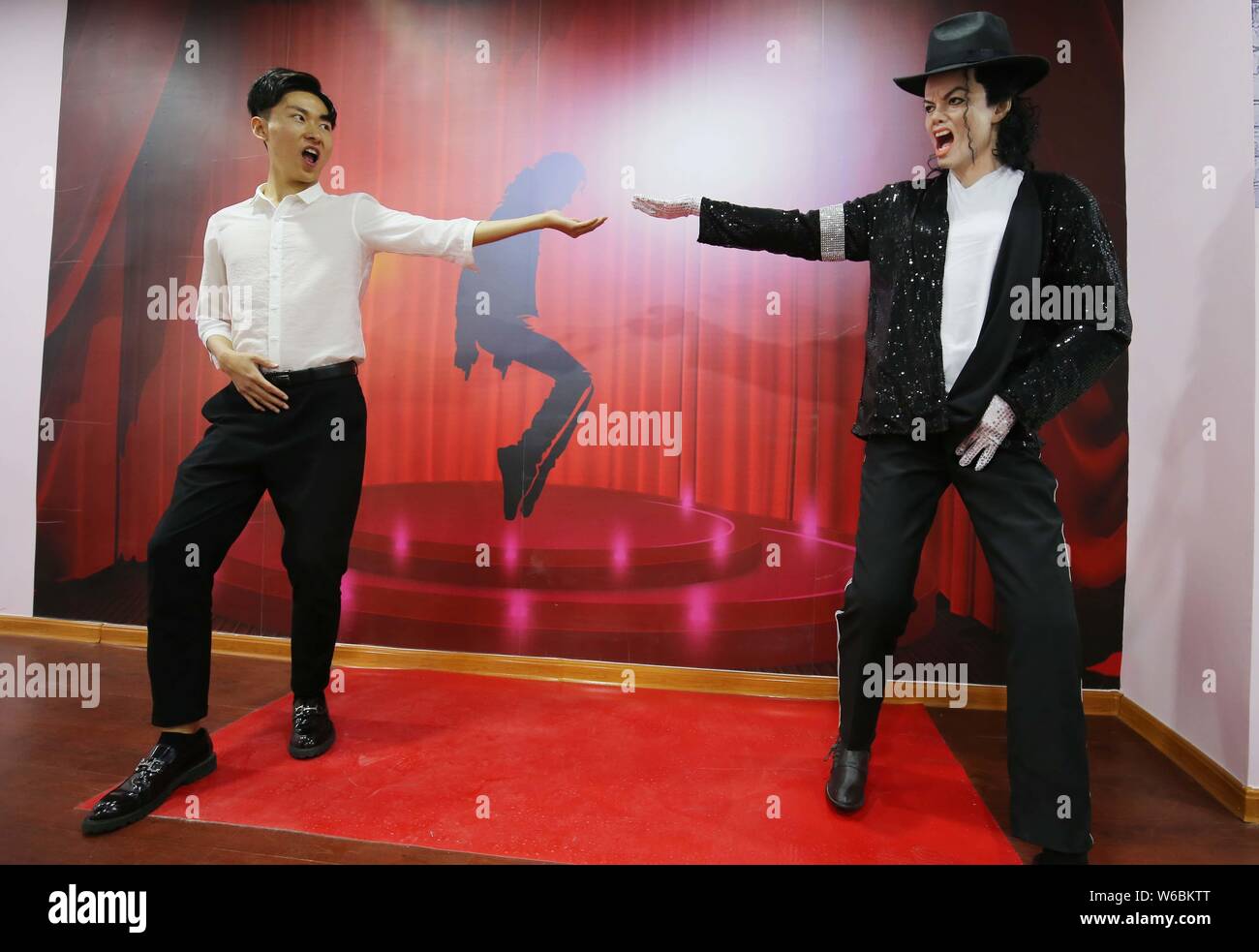 A visitor poses for photos with a wax figure of American singer and