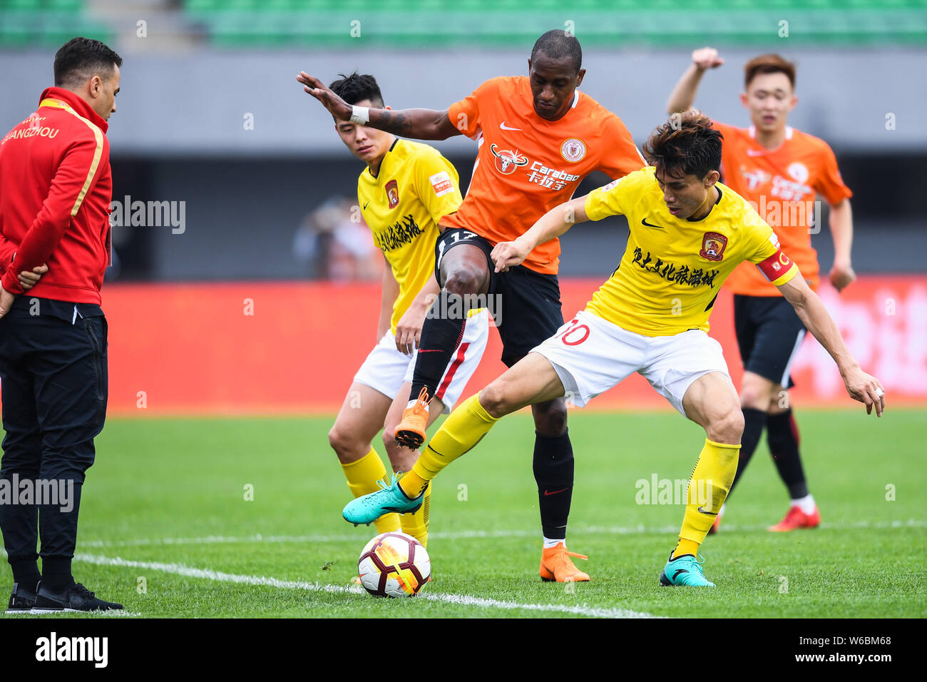 Ecuadorian football player Jaime Ayovi, center, of Beijing Renhe challenges players of Guangzhou Evergrande Taobao in their 11th round match during th Stock Photo