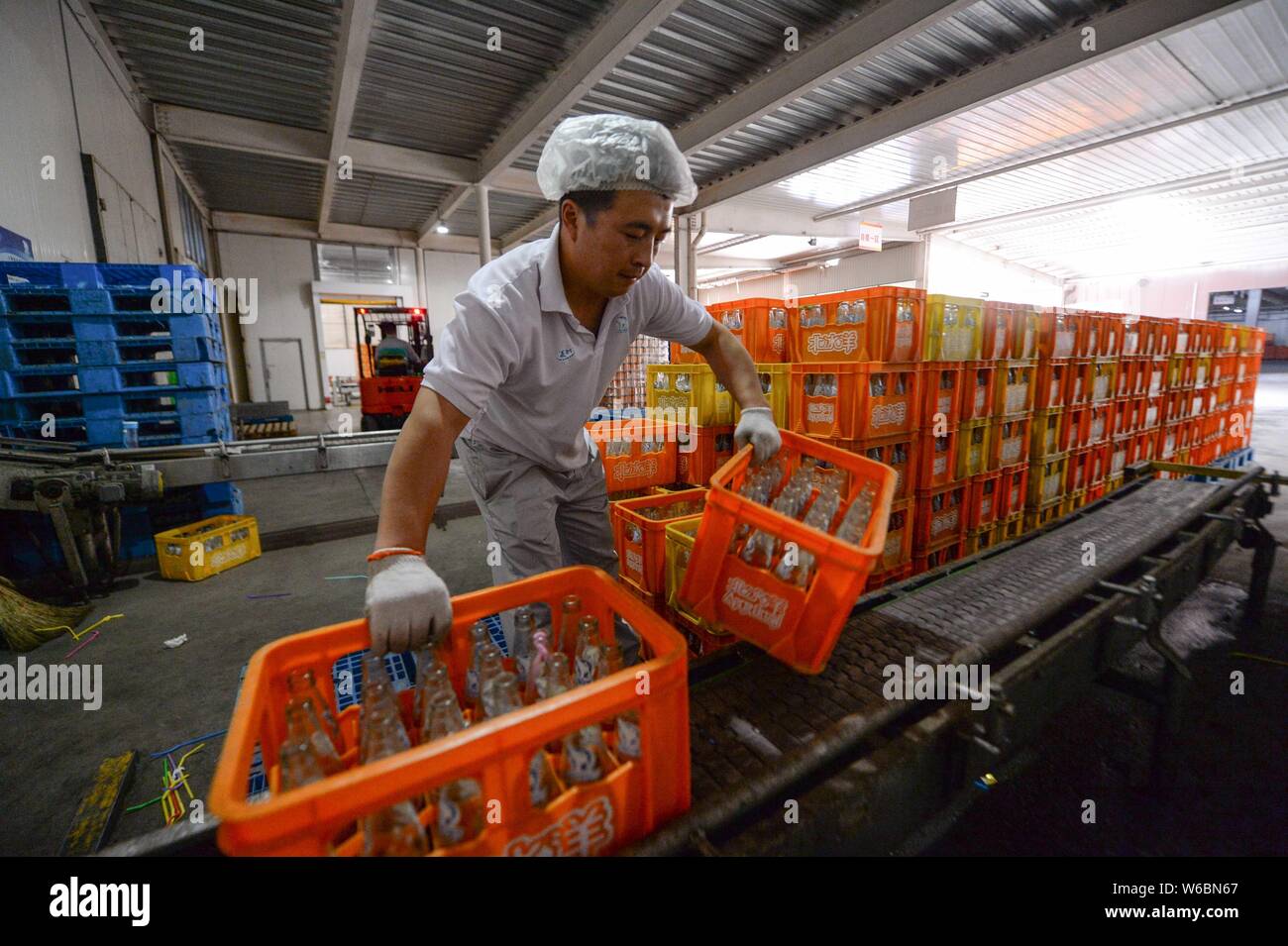 A Chinese worker puts bottles of Beibingyang orange soda into beverage ...