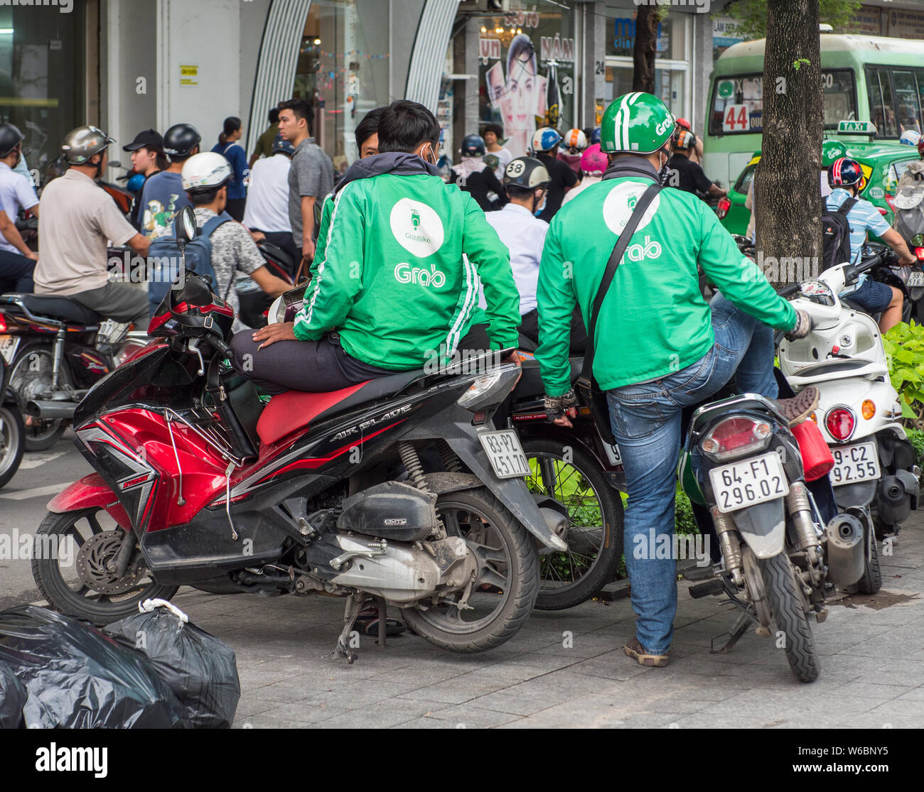 Ho Chi Minh City, Vietnam - July 28, 2017: Motorbike taxi driver from the controversial Grab ride-sharing system in downtown Ho Chi Minh City. Grab an Stock Photo