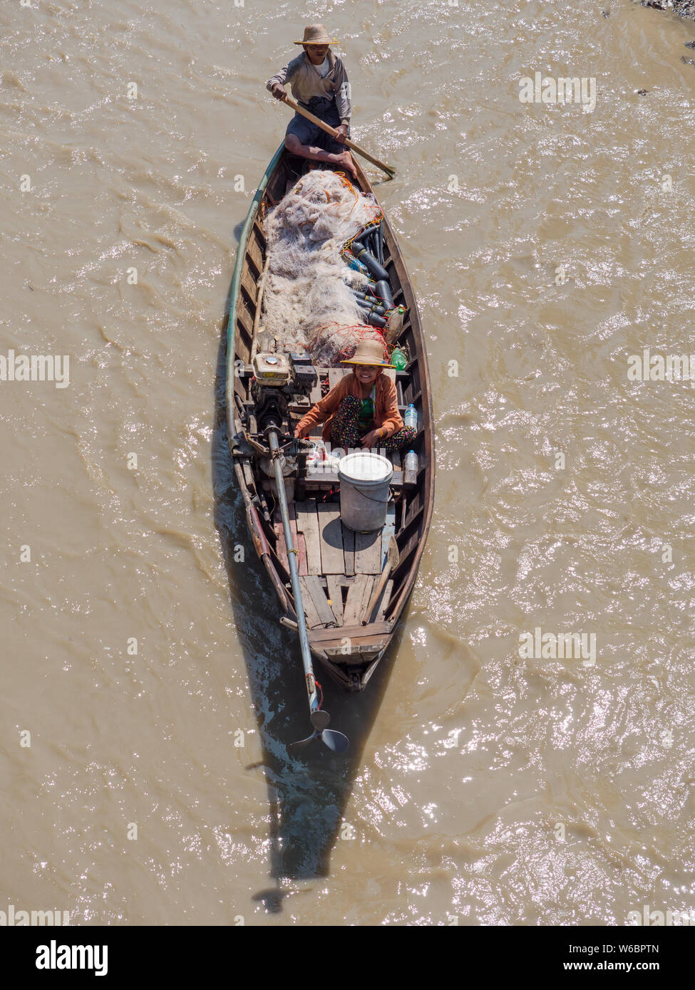 Dala, Myanmar - November 5, 2017: Small, traditional fishing vessel with husband and wife team padling down Dala River near Yangon. Stock Photo